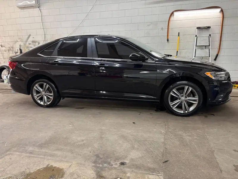 Glossy black Volkswagen Jetta with window tint in the 502 Tinted shop
